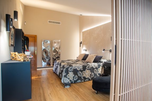 Habitación elegante con cama grande, decoraciones modernas y luz natural.