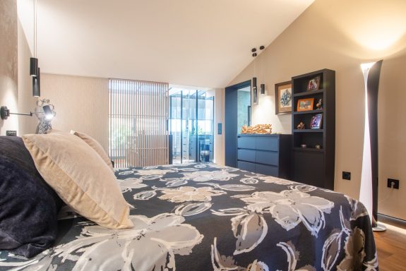 Habitación moderna con cama elegante, decoración textil con flores a medida y luz natural.