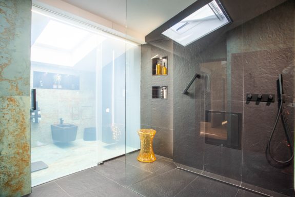 Baño moderno con separación de vidrio para el inodoro con VINILE® Privacidad, que oculta momentos, no lugares. Ducha abierta. Luz cenital.