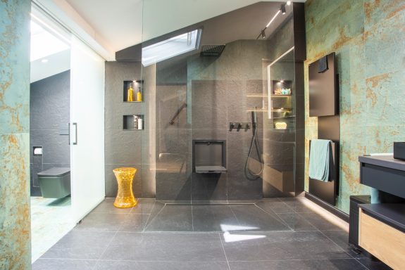 Baño moderno con ducha transparente, paredes verdes y decoración minimalista.