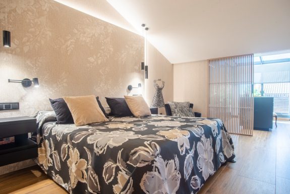 Habitación moderna con cama grande, decoración elegante y luz natural.