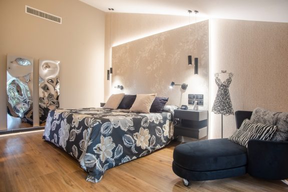 Habitación moderna con cama grande, radiadores vanguardistas y un sillón negro. Diseño elegante y acogedor.